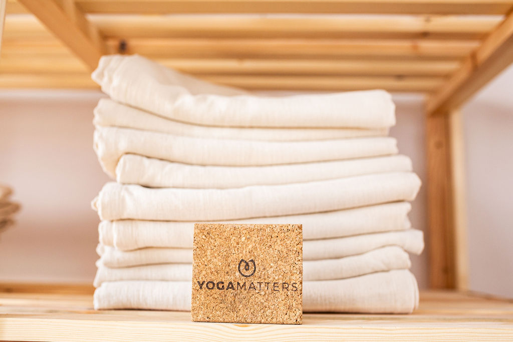 A neat stack of soft cotton blankets on a wooden shelf