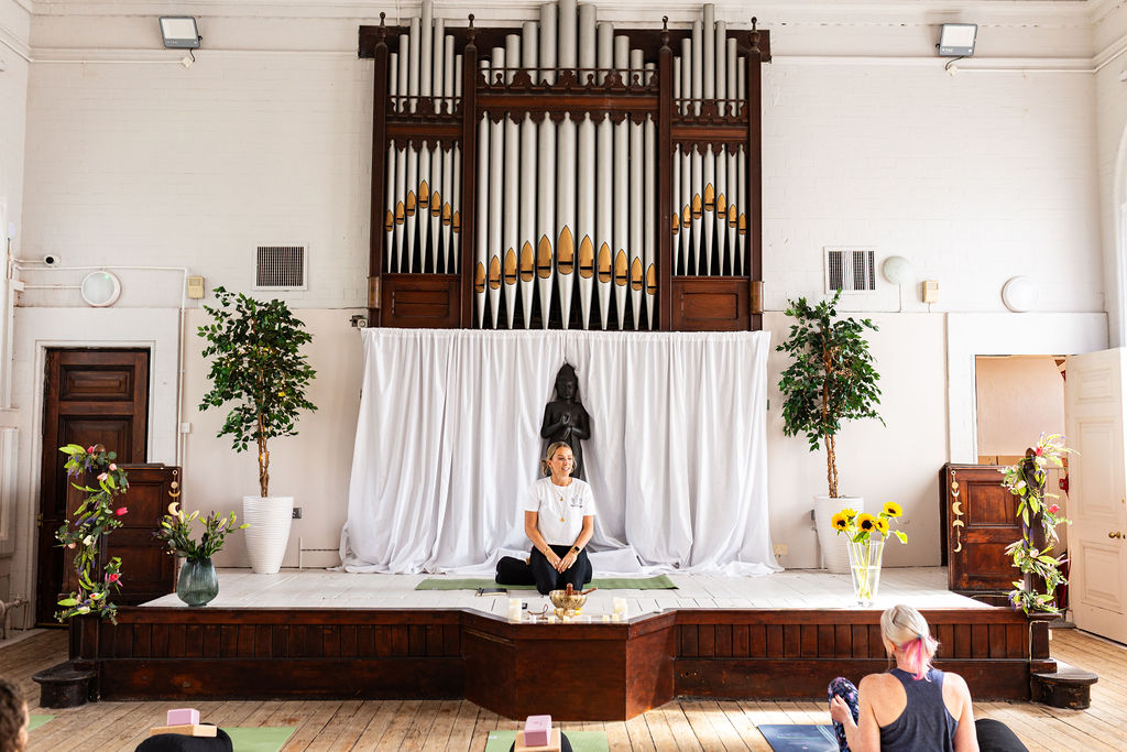 A teacher leading a class from the stage beneath the chapel's organ pipes